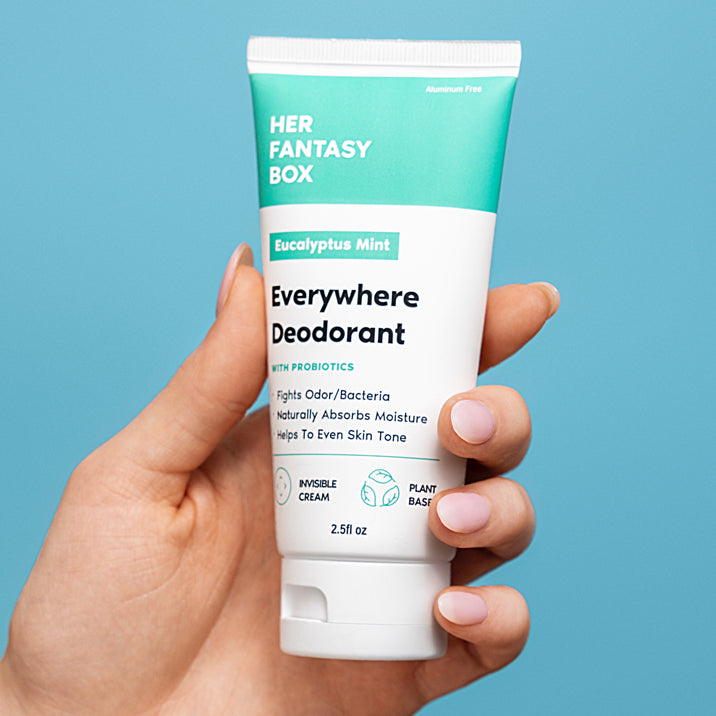 Hand holding a tube of 'Everywhere Deodorant' by Her Fantasy Box against a blue background