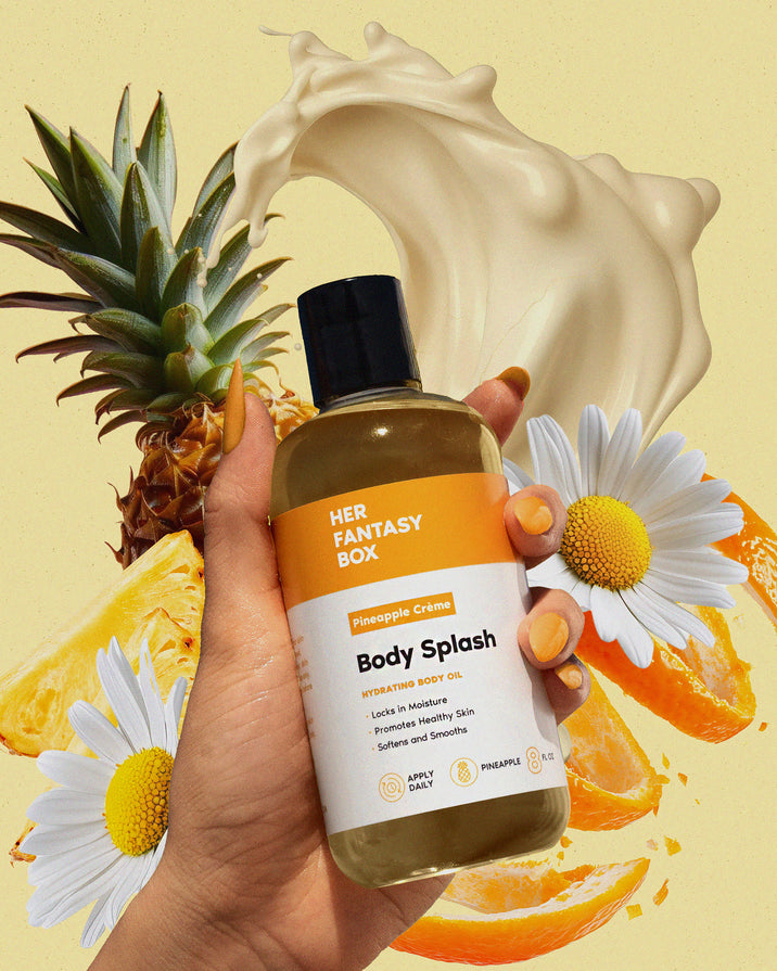 Hand holding Her Fantasy Box Pineapple Crème Body Splash hydrating body oil with pineapple, citrus, daisies, and cream splash on yellow background