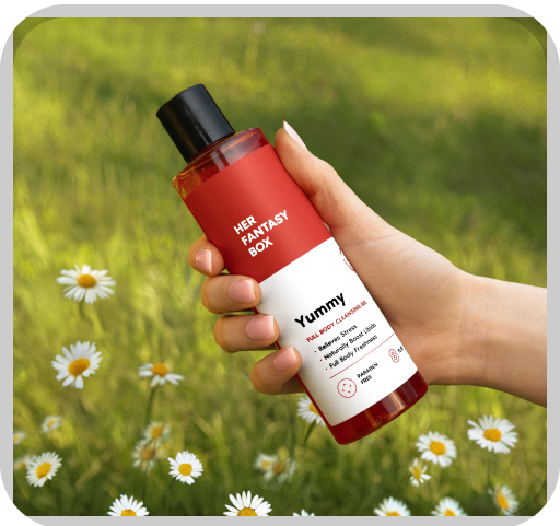 A hand holding Her Fantasy Box Yummy full body cleansing gel held outdoors over a daisy field