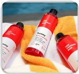 Her Fantasy Box Yummy full body cleansing gel 3-pack laid on a striped towel poolside