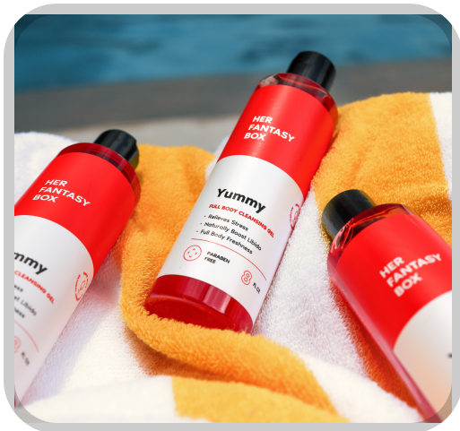 Her Fantasy Box Yummy full body cleansing gel 3-pack laid on a striped towel poolside