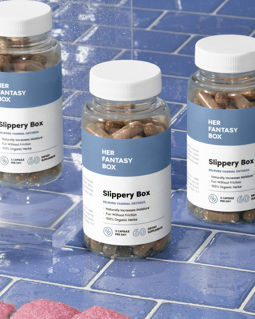 Three bottles of 'Slippery Box' capsules positioned on a blue tiled surface with water droplets around. 
