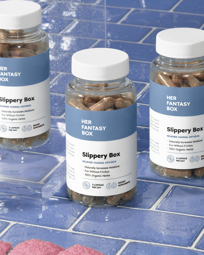 Three bottles of 'Slippery Box' capsules positioned on a blue tiled surface with water droplets around. 