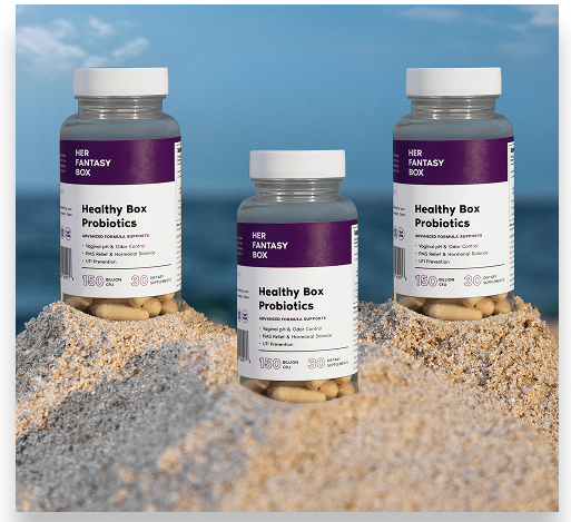 Three bottles of 'Her Fantasy Box' Healthy Box Probiotics on a sandy surface with a blue sky background.