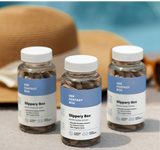 Three bottles of 'Her Fantasy Box' Slippery Box on a surface with a blurred background near a swimming pool