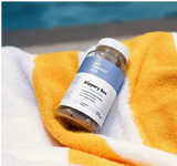 Bottle labeled 'Slippery Box' on a yellow and white towel with a blurred blue background