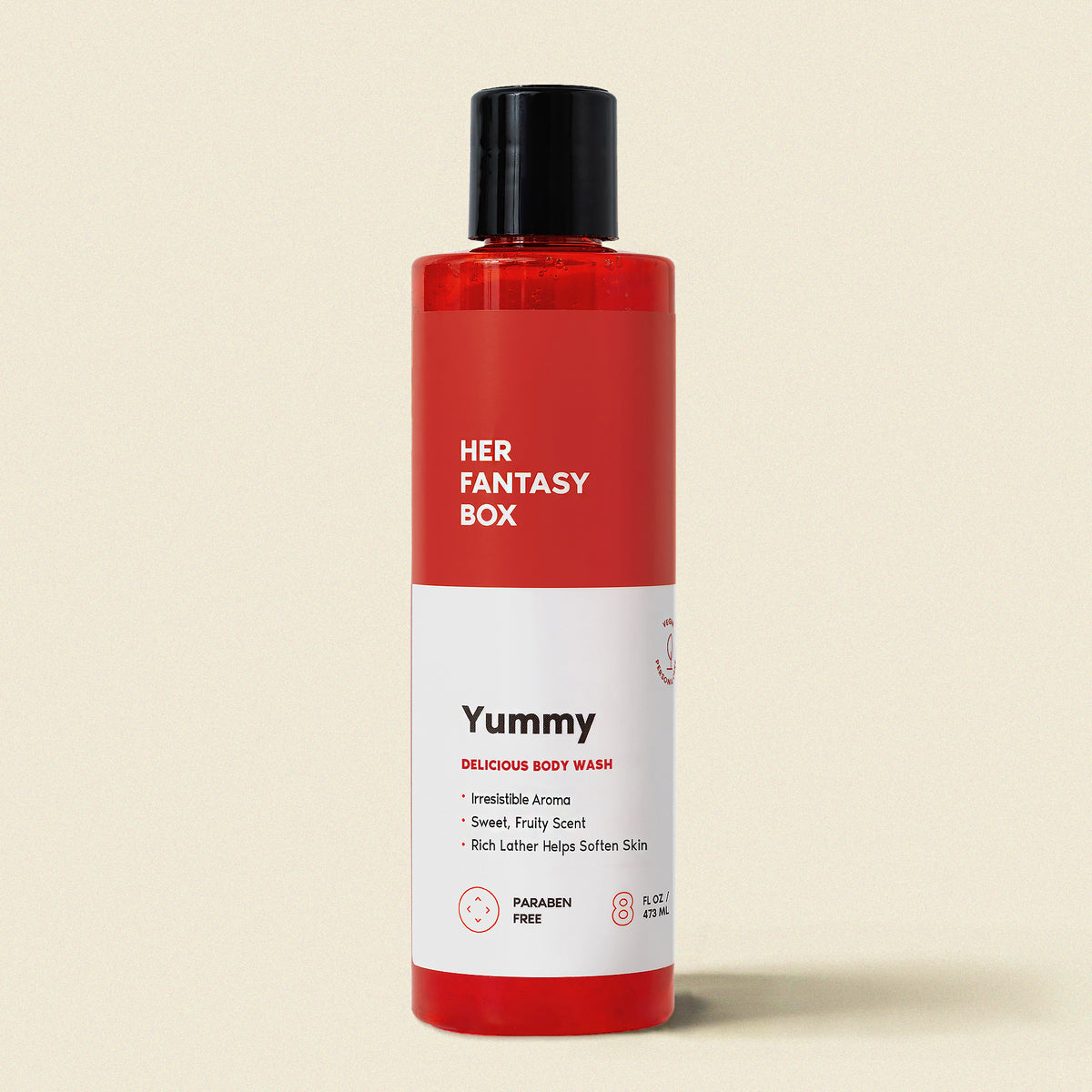 Red bottle of 'Yummy' body wash with a black cap on a beige background