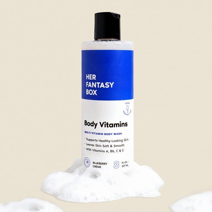 Her Fantasy Box Body Vitamins Blueberry Crème multi-vitamin body wash 8 fl oz bottle surrounded by lather on neutral background