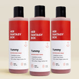Three bottles of 'Her Fantasy Box Yummy' body wash on a beige background